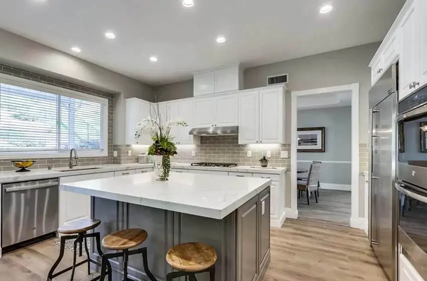Kitchen with dark gray cabinet island and white cabinets