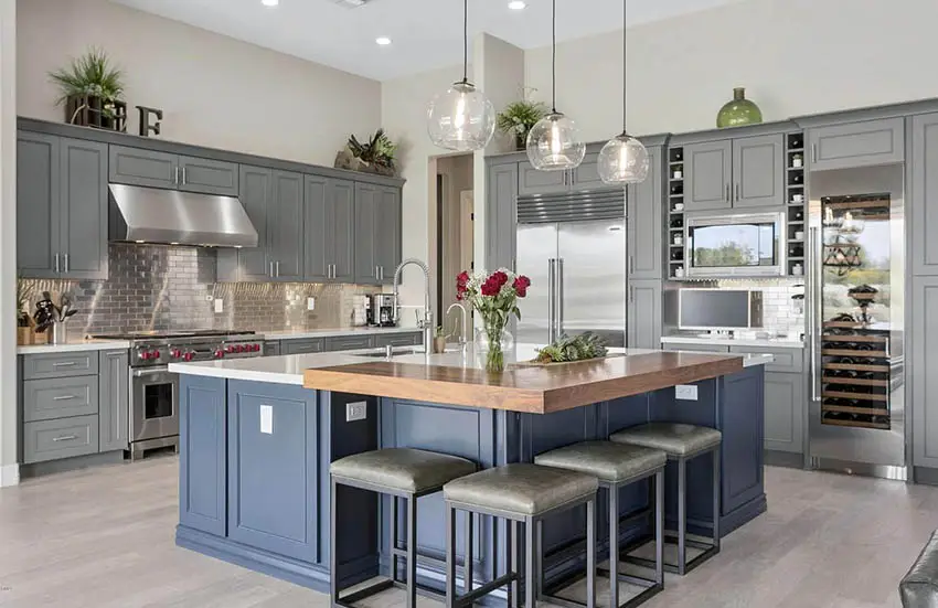 Kitchen with gray cabinets and blue gray island with white quartz and butcher block counters