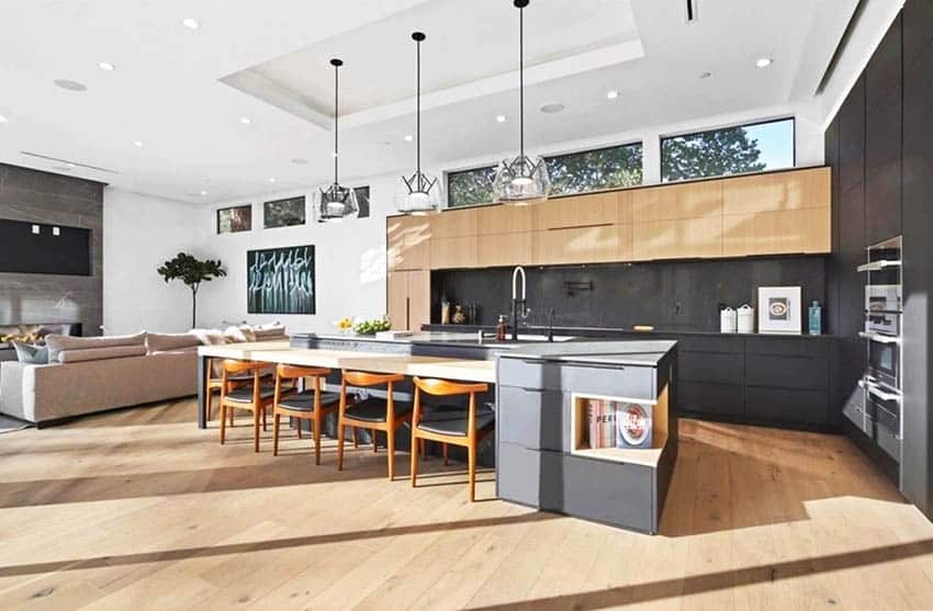 Large modern kitchen with dark gray cabinets light wood cabinets island with seating light wood flooring