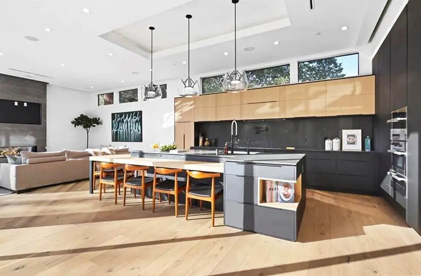 Large modern kitchen with dark gray cabinets light wood cabinets island with seating light wood flooring