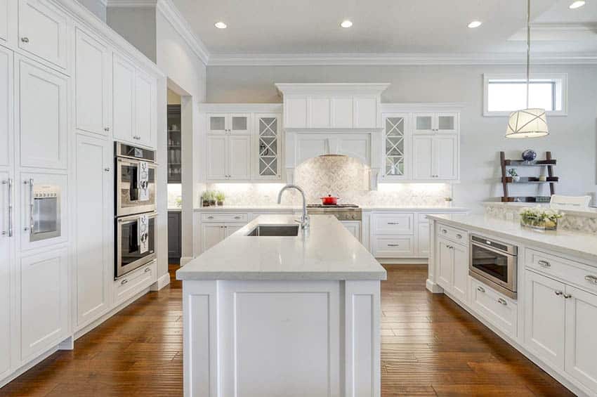 Large open concept kitchen with caesarstone countertops white cabinets wood flooring