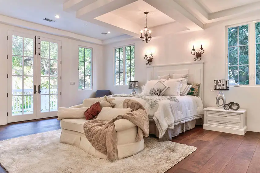 Master bedroom with french doors, plush loveseat and engineered acacia flooring