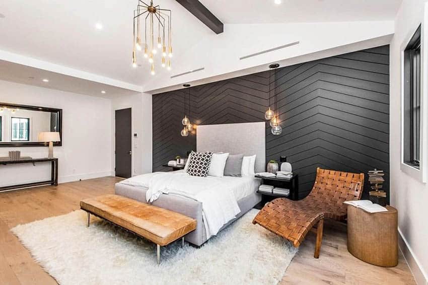 Modern farmhouse bedroom design with wood floors & beam, black accent wall and pendant lights