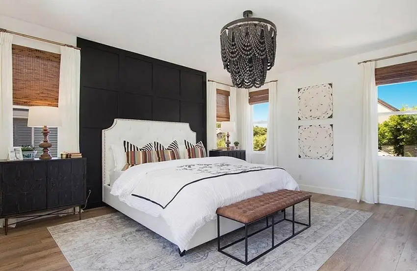 Modern farmhouse bedroom with black paneled accent wall behind bed beaded hanging chandelier