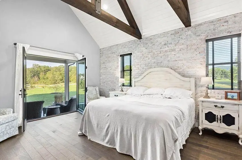 Modern farmhouse master bedroom with cathedral ceiling whitewashed walls black door window frames wood flooring