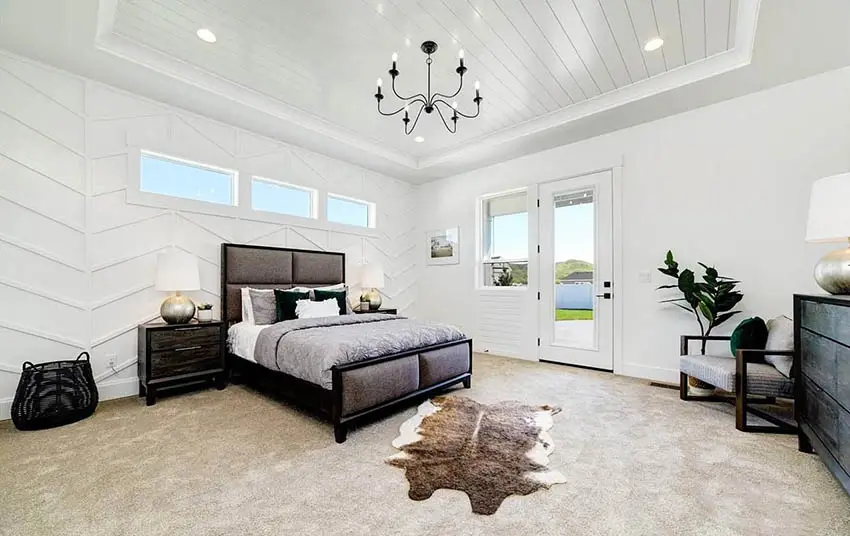 Modern farmhouse master bedroom with shiplap ceiling paneled walls and chandelier