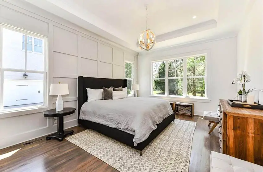Modern farmhouse master bedroom with tray ceiling globe chandelier and paneled wall