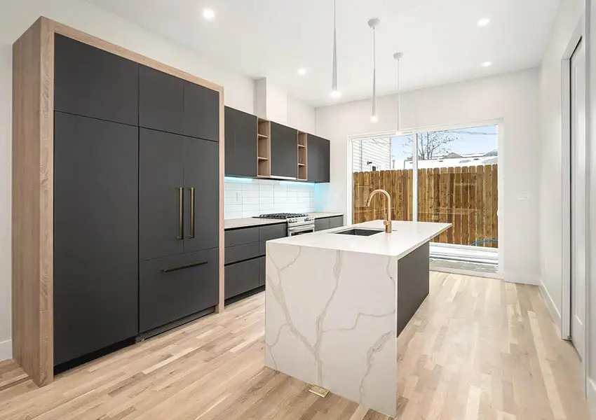 Modern kitchen with dark cabinets wood trim and quartz waterfall island