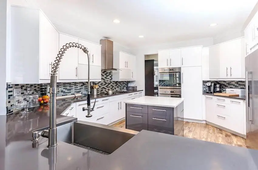 Modern kitchen with gray quartz peninsula and white quartz island white cabinets