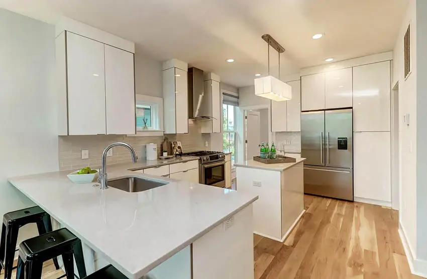 Modern kitchen with small dining peninsula island and quartz countertops white cabinets