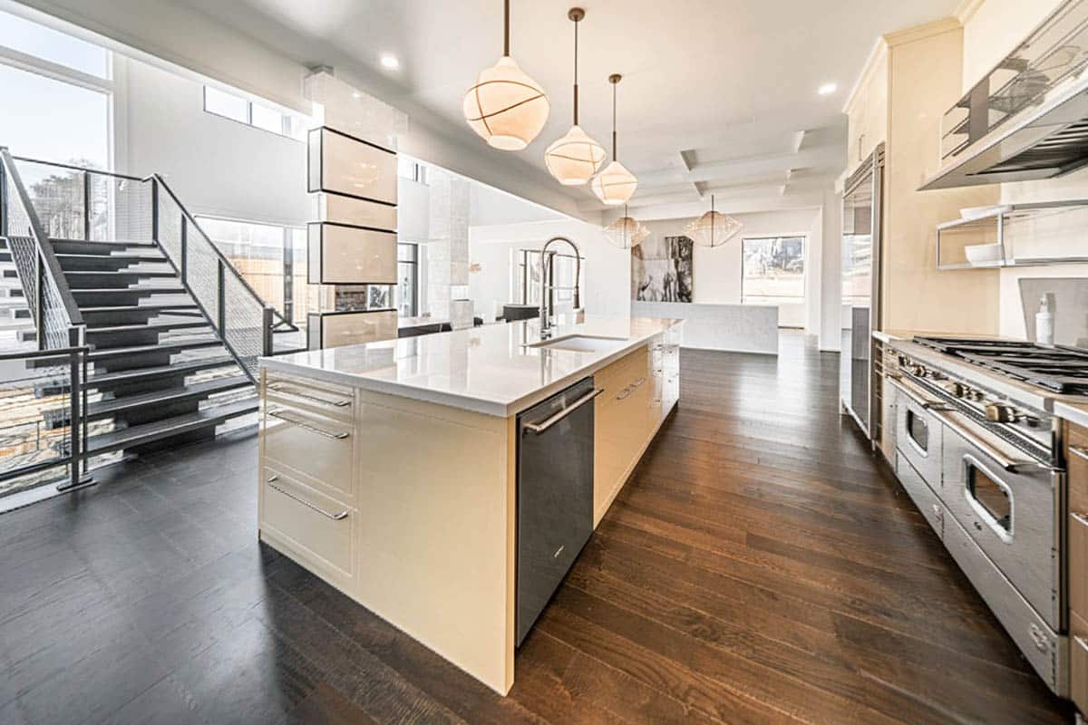 Open kitchen with glossy cabinets, looped pendant lighting and double ovens