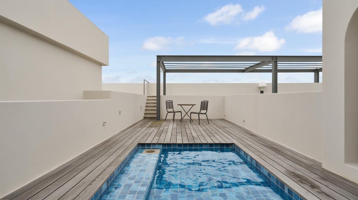 Minimalist modern rooftop plunge pool with blue tile trim and grey wood deck planks