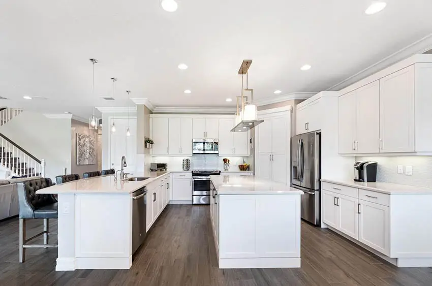 Open concept kitchen with large island and peninsula white quartz counters white cabinets