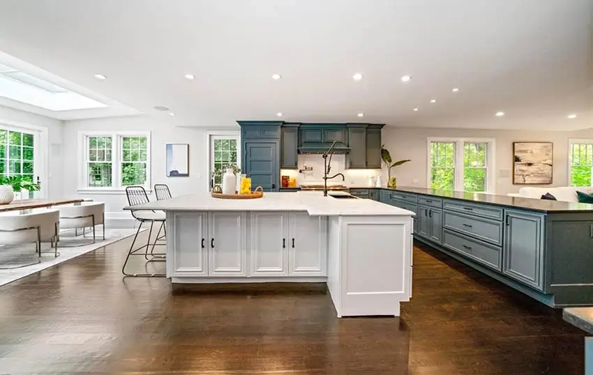 Open concept kitchen with white t shaped island large green cabinet peninsula wood flooring