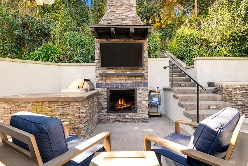 Outdoor patio with waterproof tv and stacked stone fireplace with attached barbecue