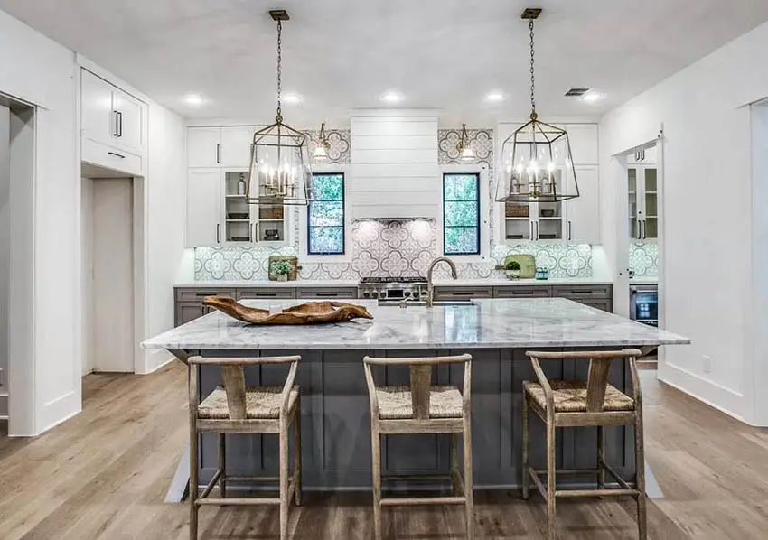 Transitional kitchen with dark gray base cabinets island and white upper cabinets marble counters and chandeliers