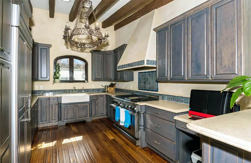 Tuscan kitchen with dark gray distressed cabinets rustic chandelier wood beams and bamboo flooring