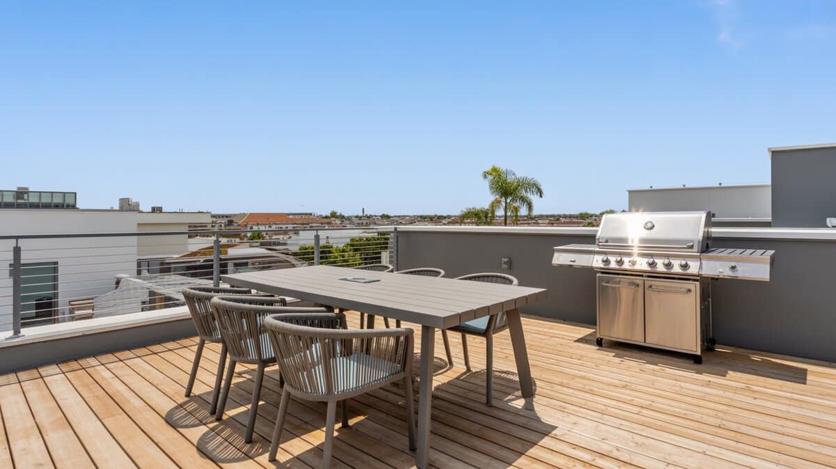 Urban flat roof deck with natural wood flooring, cable railing, and stainless BBQ grill
