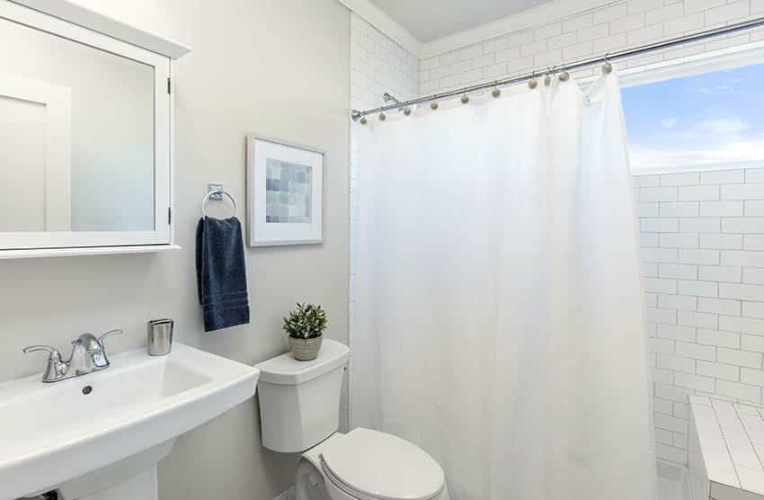 Shower with subway tile and long white shower curtain