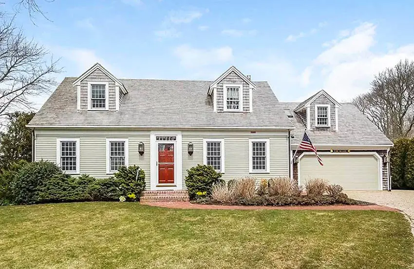 Cape cod home with white window trim and red door