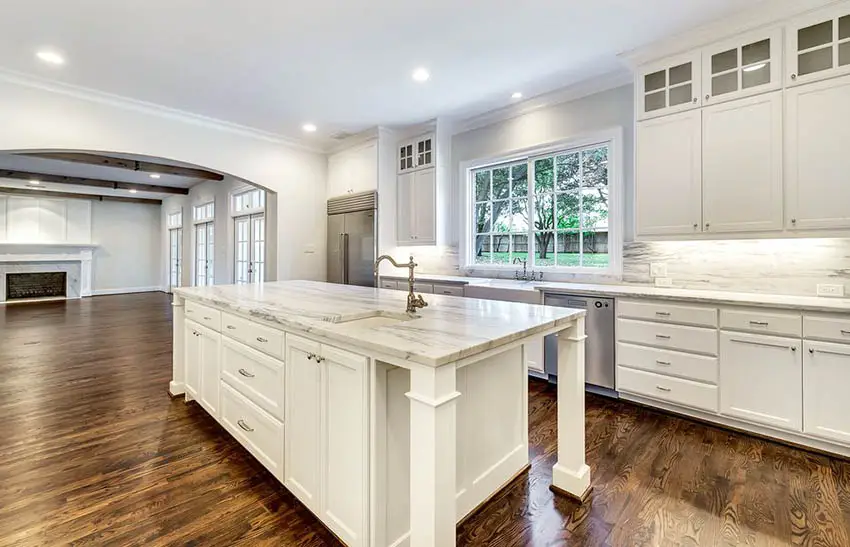Cape cod kitchen with white cabinets casement windows stone backsplash and crown molding