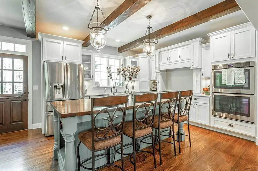 Cape cod kitchen with white cabinets light green island wood beam ceiling wood flooring