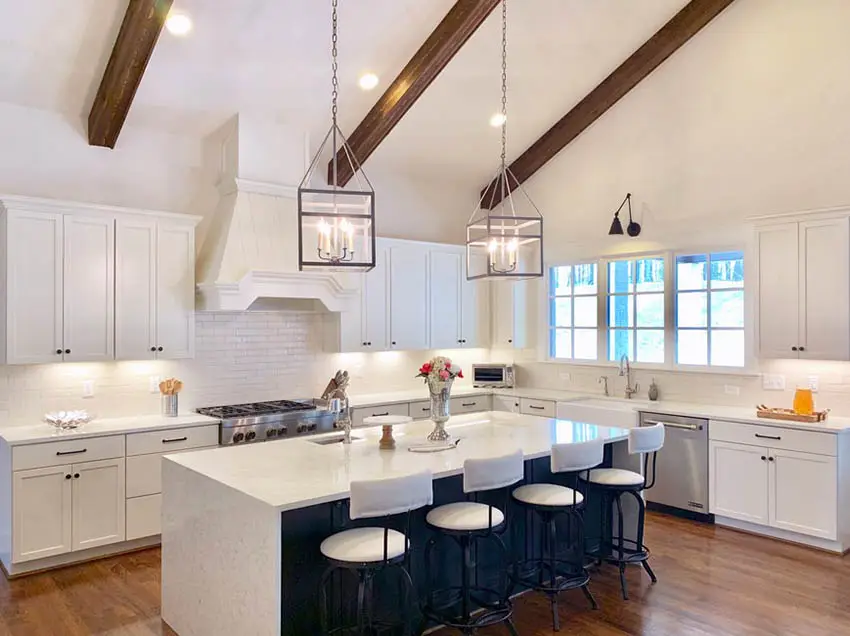 Cape cod style kitchen with vaulted ceiling wood beams white cabinets navy island white quartz counters