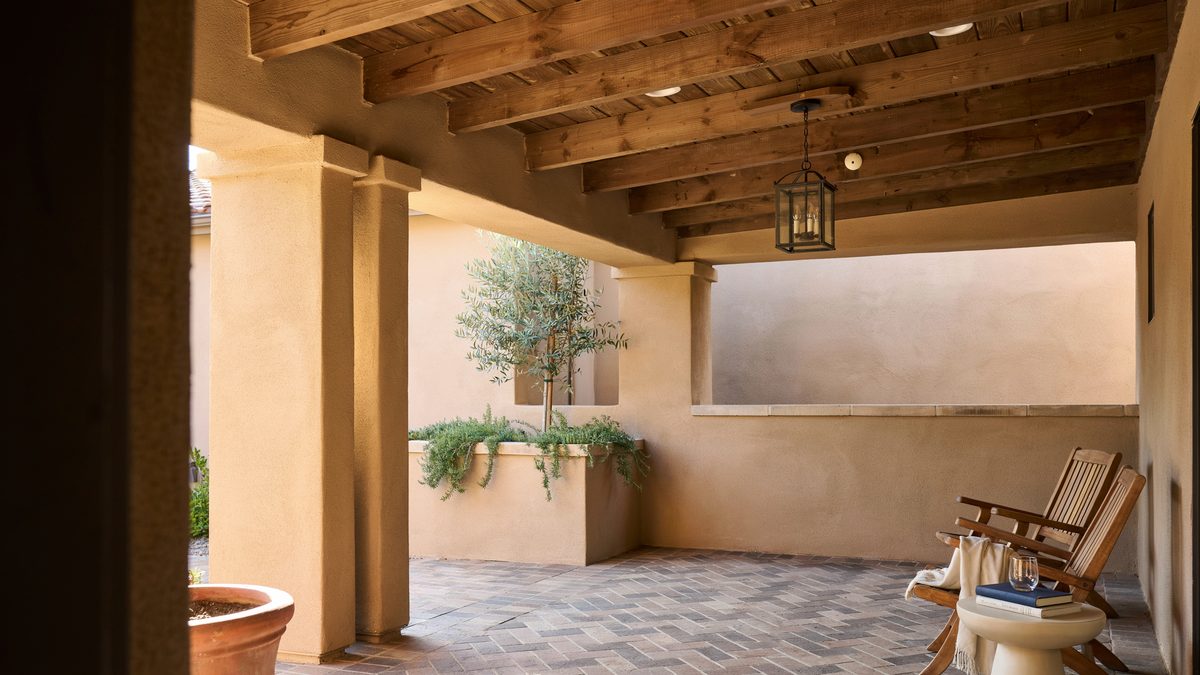 Covered stucco patio with exposed wood beam ceiling and hanging lantern