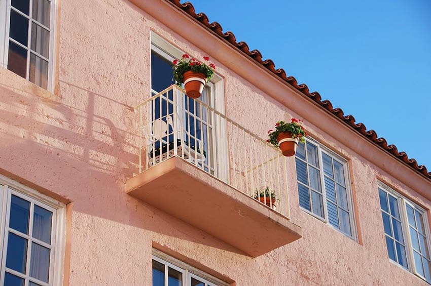 Exterior stucco wall on house with balcony and flowerpots