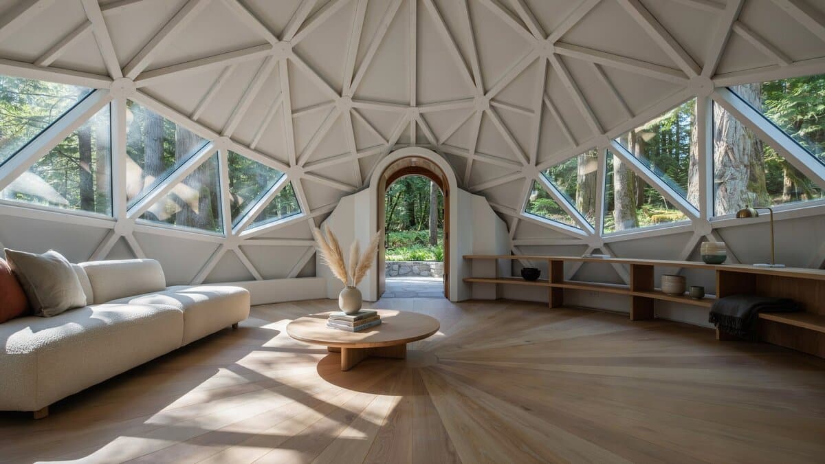 White geodesic dome interior with triangular windows framing a forest