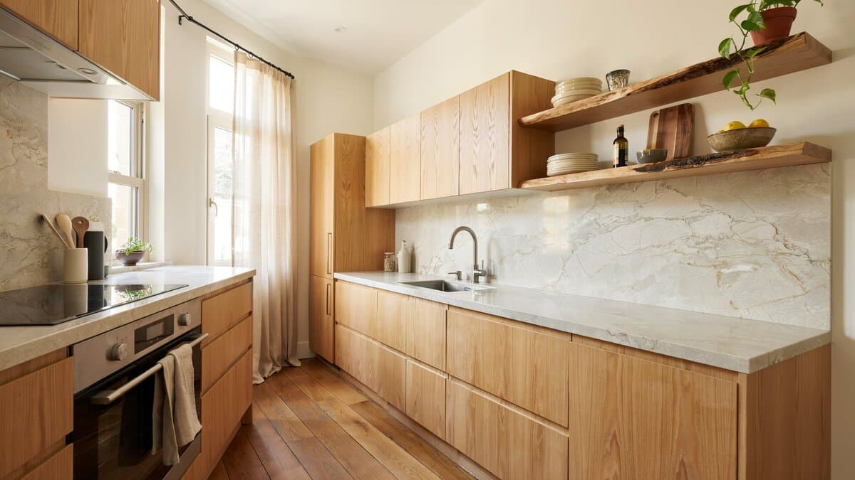 Quartzite counters and backsplash beside wood veneer cabinets and live edge shelving