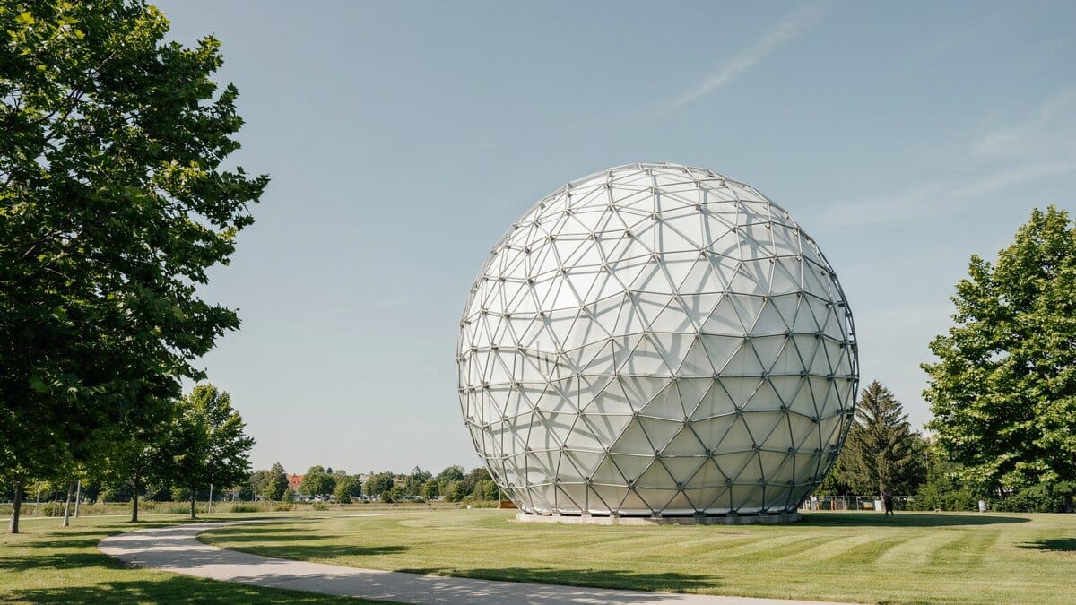 Full white geodesic sphere with steel triangle framework on a lawn