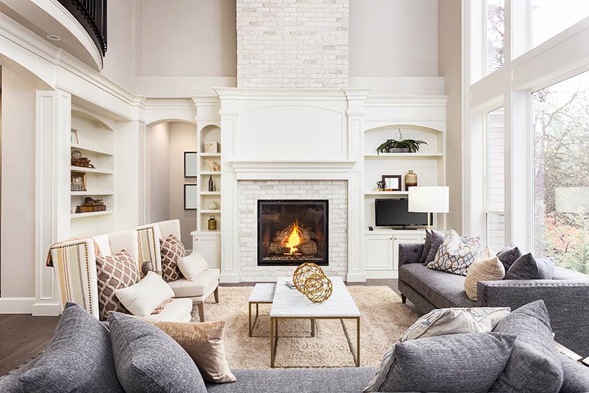 Living room with gas fireplace, white built-in shelving and high ceilings