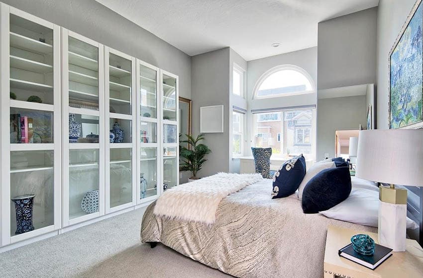 Master bedroom with built in cabinet with glass door shelving cabinets