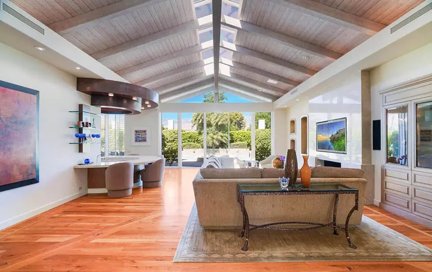 Mid century modern living room with wood plank cathedral ceiling and skylights