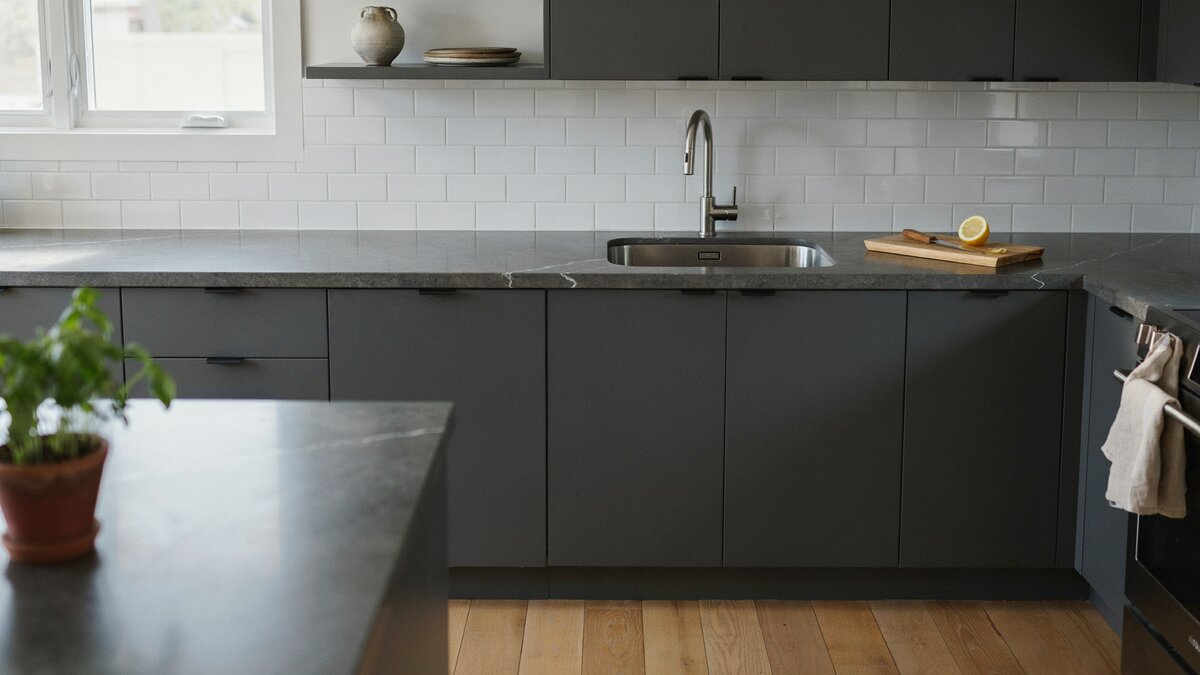 Sleek kitchen featuring dark gray quartzite countertops beside a crisp white backsplash
