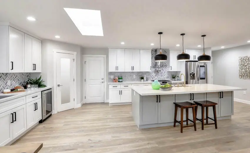 Open concept kitchen with quartz countertops skylight white cabinets gray island