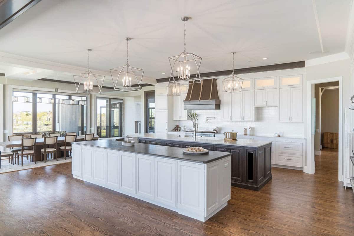 Open layout kitchen with two long islands contrasting quartz countertops two tone cabinets
