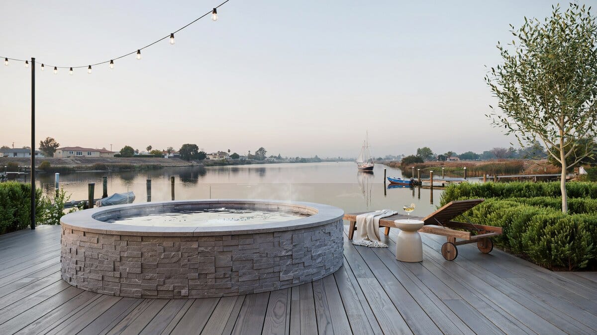 Round stone jacuzzi on a wood deck overlooking a waterfront canal