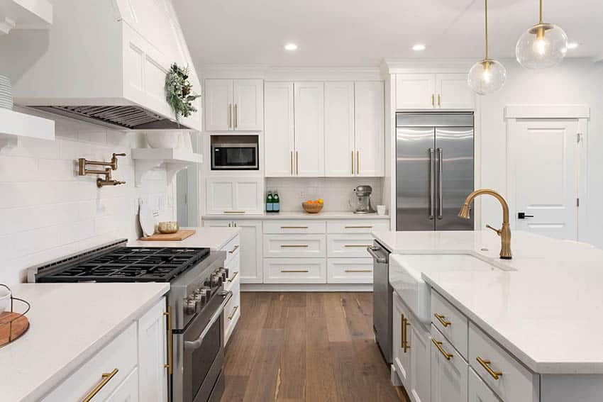 Beautiful kitchen with white shaker style cabinets, gold hardware and white quartz countertops