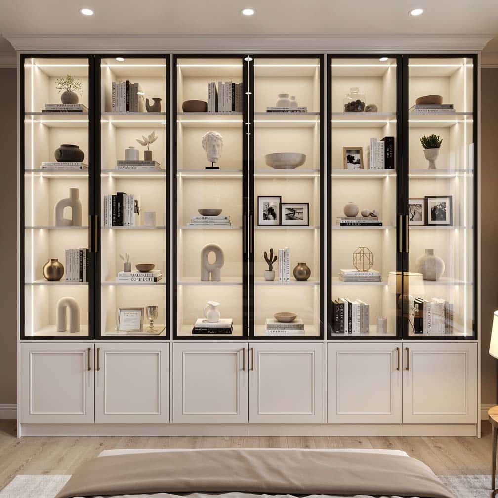 Built-in glass-door display cabinets with interior LED lighting in a bright bedroom