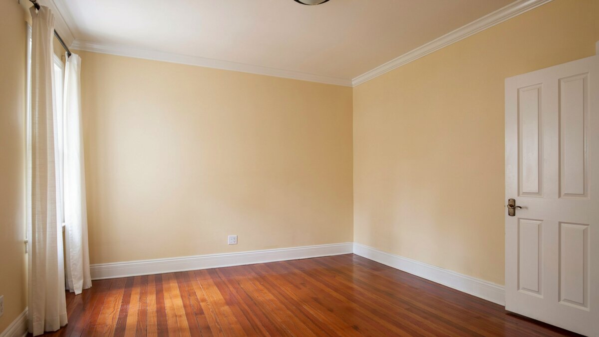 Empty bedroom with buttery yellow walls, white six panel door and moldings