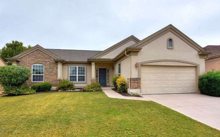 Stucco and brick house with large lawn and driveway