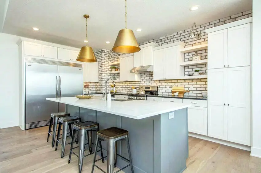 Kitchen with white cabinets gray island gold pendant lights and hardwood floors