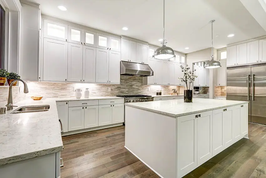 Kitchen With White Shaker Cabinets Light Color Marble Countertops Chrome Pendant Lighting Wood Floors Ss .webp