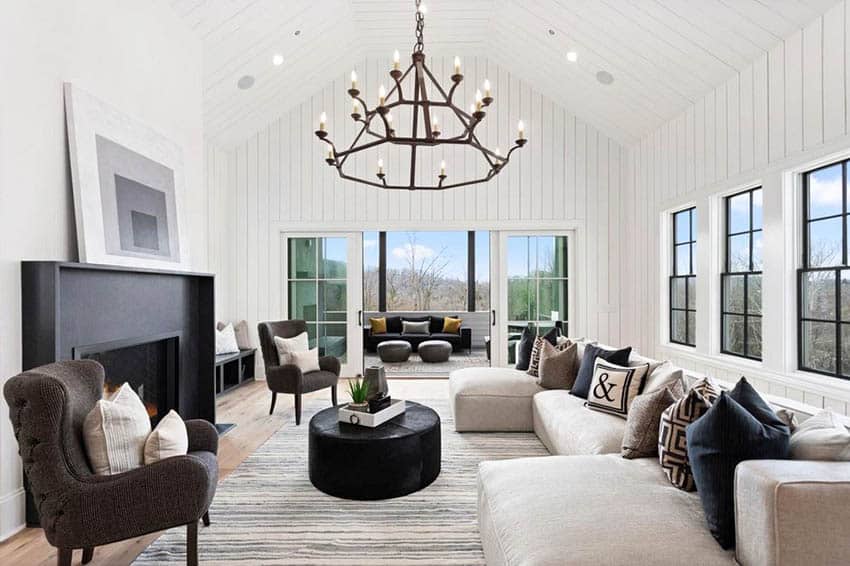 Living room with black framed windows chandelier and shiplap walls and ceiling