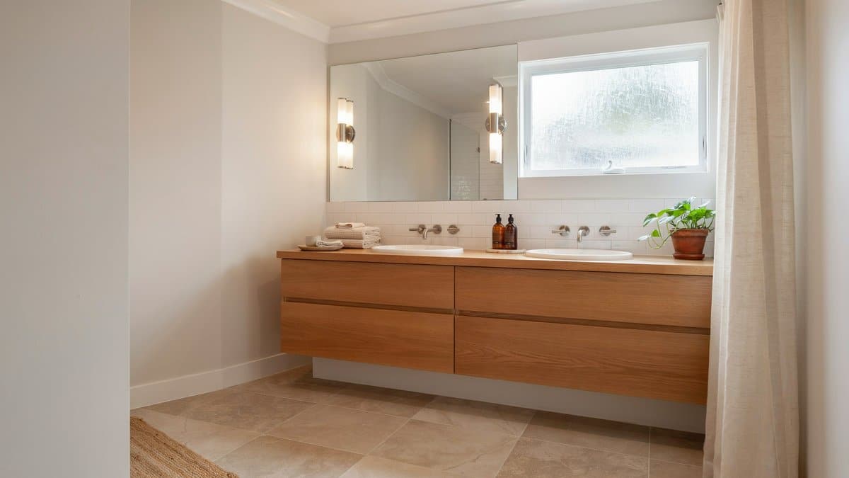 Warm gray master bathroom with beige tile and a wood double vanity