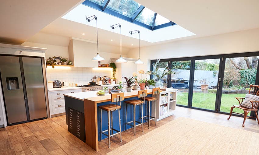 Bright kitchen design with skylight large sliding door and blue island with wood breakfast bar 