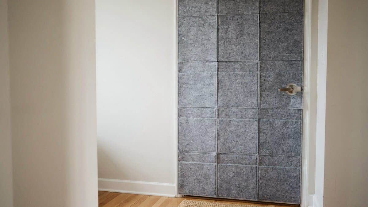 Gray felt acoustic tile kit covering an interior door in a hallway