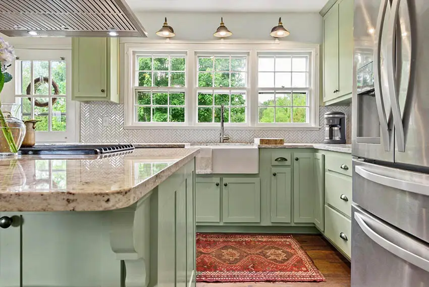 Kitchen with mint green cabinets herringbone style tile backsplash